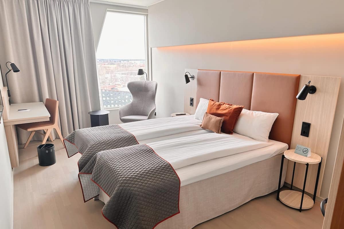 Een hotelkamer met een groot bed, een bureau, een stoel en uitzicht op de stad.