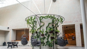 A modern interior with a central circular column surrounded by hanging chairs and a foosball table. - Quality Hotel Arlanda XPO (Arlandastad)