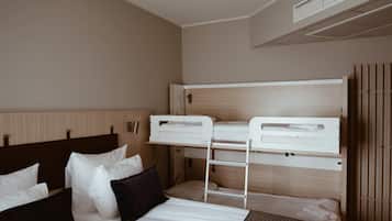 A hotel room with a bunk bed, a single bed, and a wooden headboard.