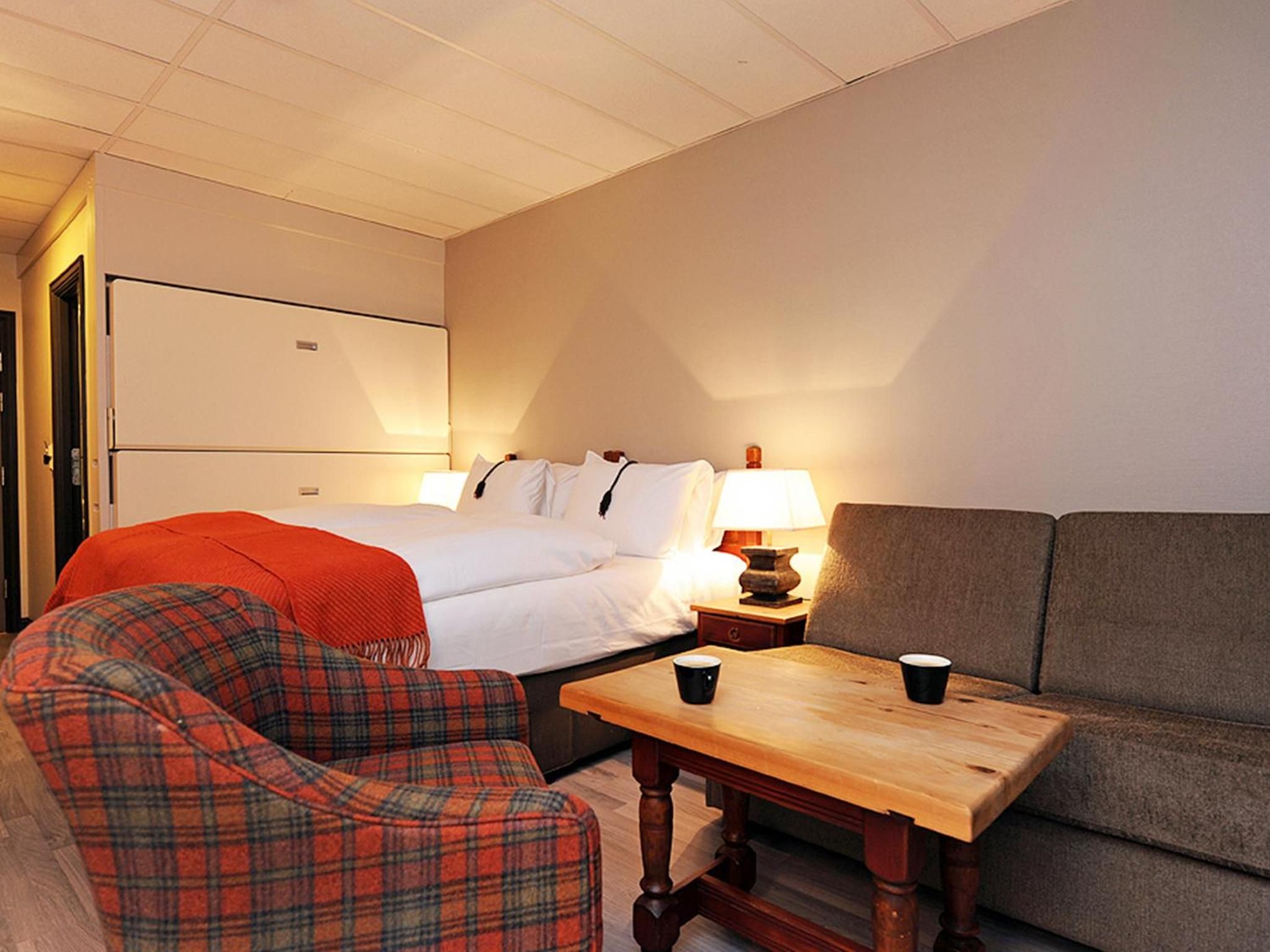 Una camera d'albergo con un letto, un divano, una sedia, un tavolo e una lampada.