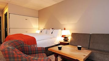 A hotel room with a bed, a sofa, a chair, a table, and a lamp.
