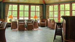 A spacious room with large windows, wicker furniture, and a high ceiling. - Hunderfossen Hotell & Resort Hafjell (Lillehammer)