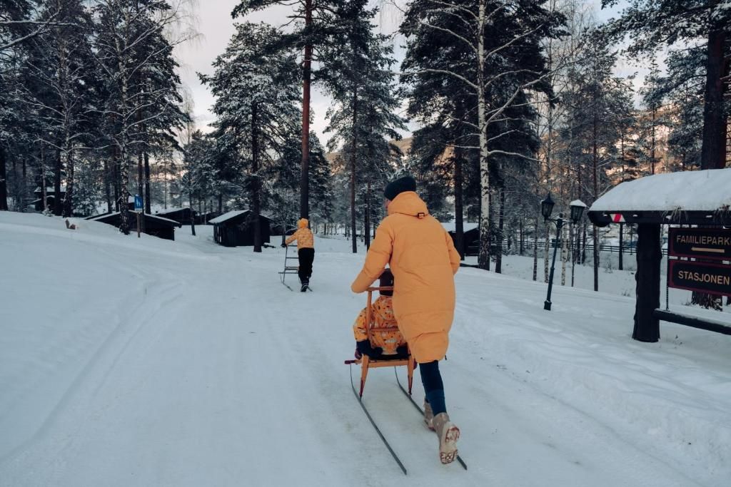 A snowy outdoor area with a sled being pulled by a person.