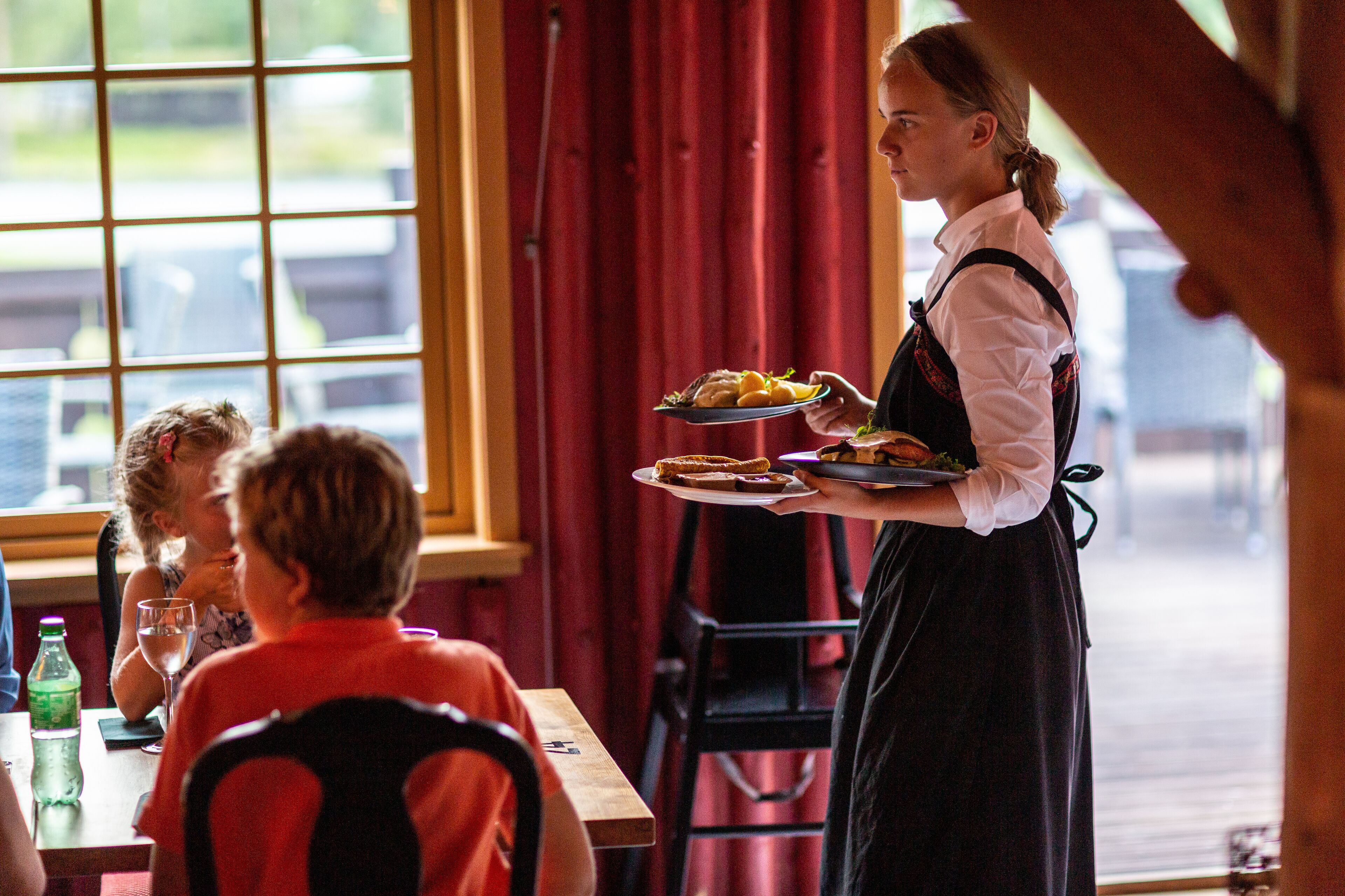 A person serving food at a table with a window view.