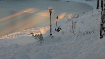 Un paysage enneigé avec un lac gelé, des arbres chargés de neige et un lampadaire.