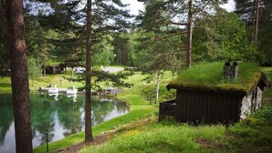 A serene lakeside setting with a wooden cabin, a swan on the water, and a boat docked nearby. - Hunderfossen Hotell & Resort Hafjell (Lillehammer)
