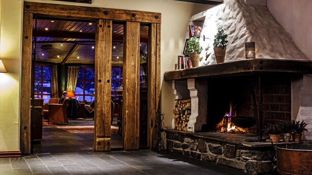 A cozy interior with a fireplace, wooden beams, and a sign reading "Simenstugu". - Hunderfossen Hotell & Resort Hafjell (Lillehammer)
