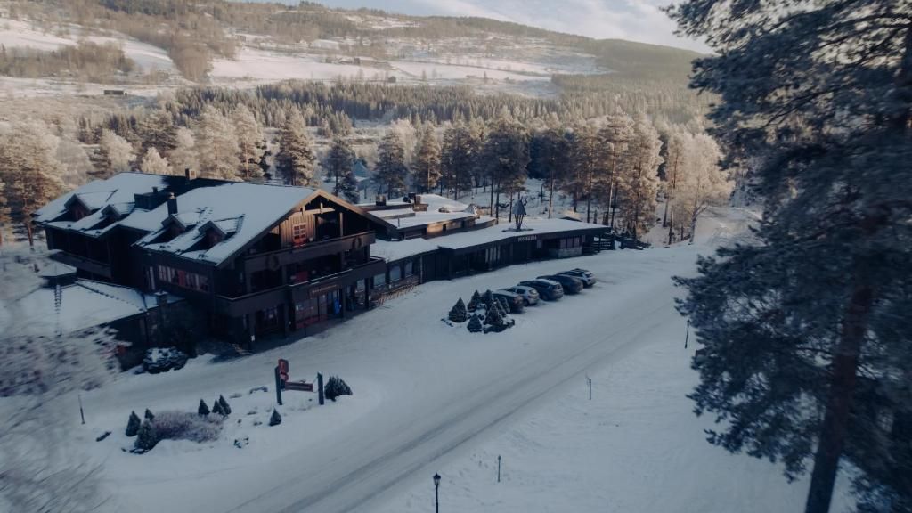 A lodge with a large building and a smaller annex, surrounded by snow-covered trees and a clear sky.
