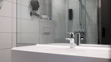 A modern bathroom with a white sink, a mirror, and a shower area.