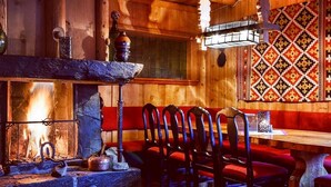 A cozy wooden interior with a fireplace, wooden benches, and a patterned wall hanging. - Hunderfossen Hotell & Resort Hafjell (Lillehammer)