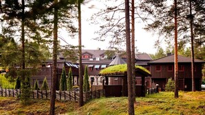 A rustic cabin with a thatched roof, surrounded by tall trees and a wooden fence. - Hunderfossen Hotell & Resort Hafjell (Lillehammer)