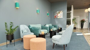 A modern lounge area with teal and white chairs, a coffee table, and a potted plant.