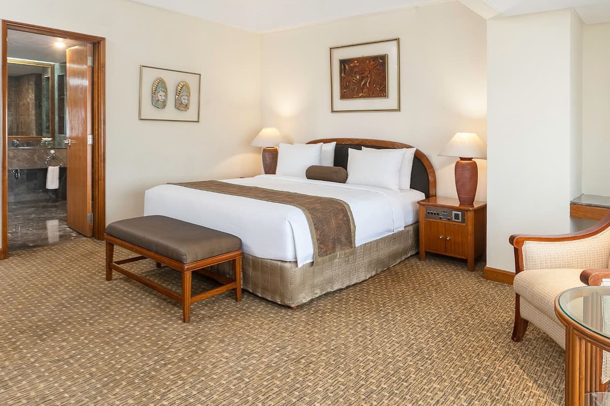 Ein Hotelzimmer mit Bett, Stuhl, Nachttisch und kleinem Tisch.