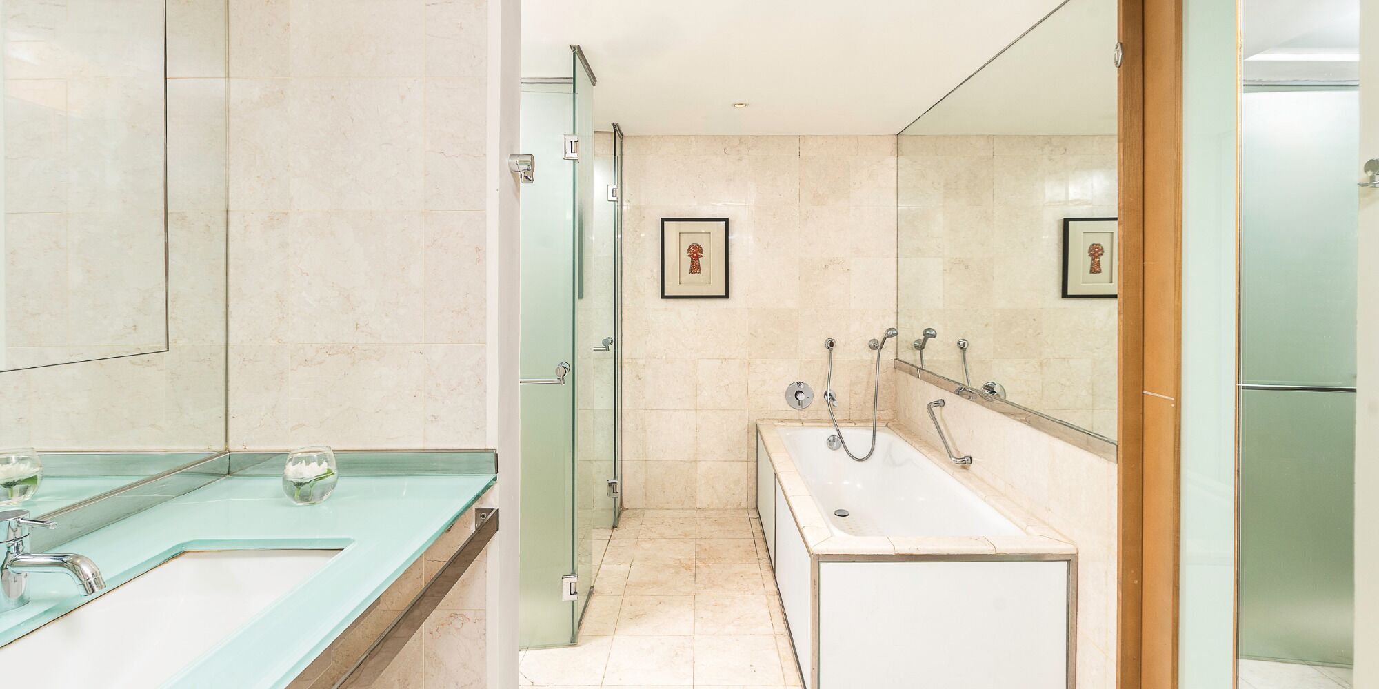 Un baño moderno con cabina de ducha de vidrio, una bañera y un lavabo con encimera de cristal.