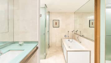 A modern bathroom with a glass shower enclosure, a bathtub, and a sink with a glass countertop.