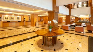 Un hall amplio con mostrador de recepción, zona de estar y un centro de mesa decorativo con planta.