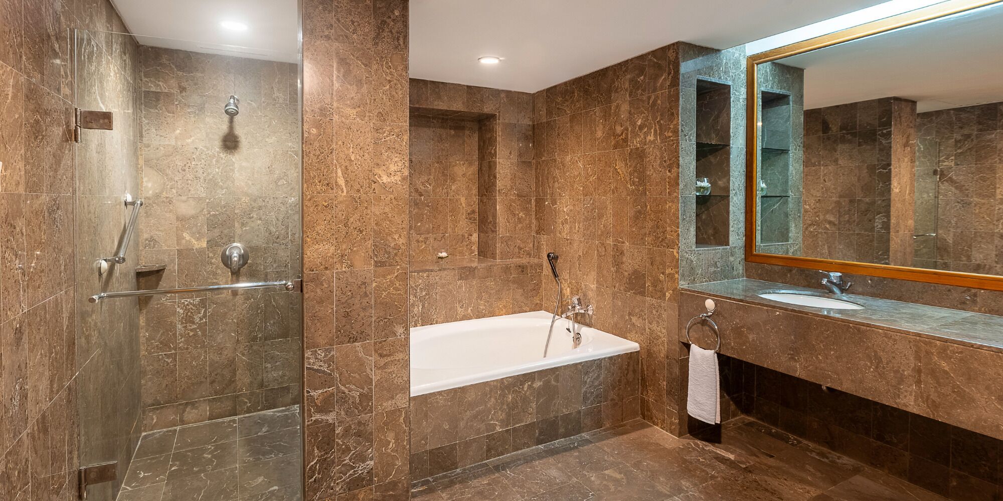 A modern bathroom with a glass-enclosed shower, a freestanding bathtub, and a vanity with a large mirror.