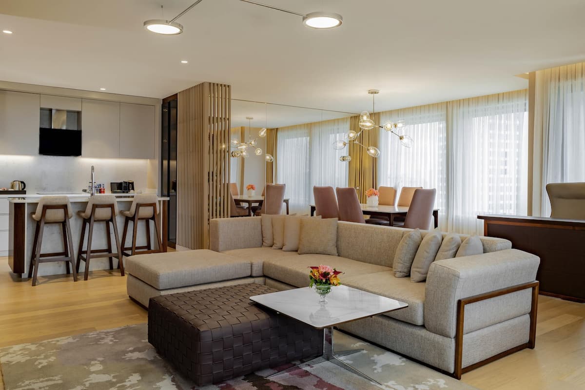 A modern living room with a sectional sofa, a coffee table, and a dining area with a chandelier.