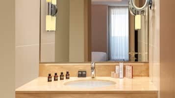 A modern bathroom with a large mirror, a sink, and two towels hanging on the wall.