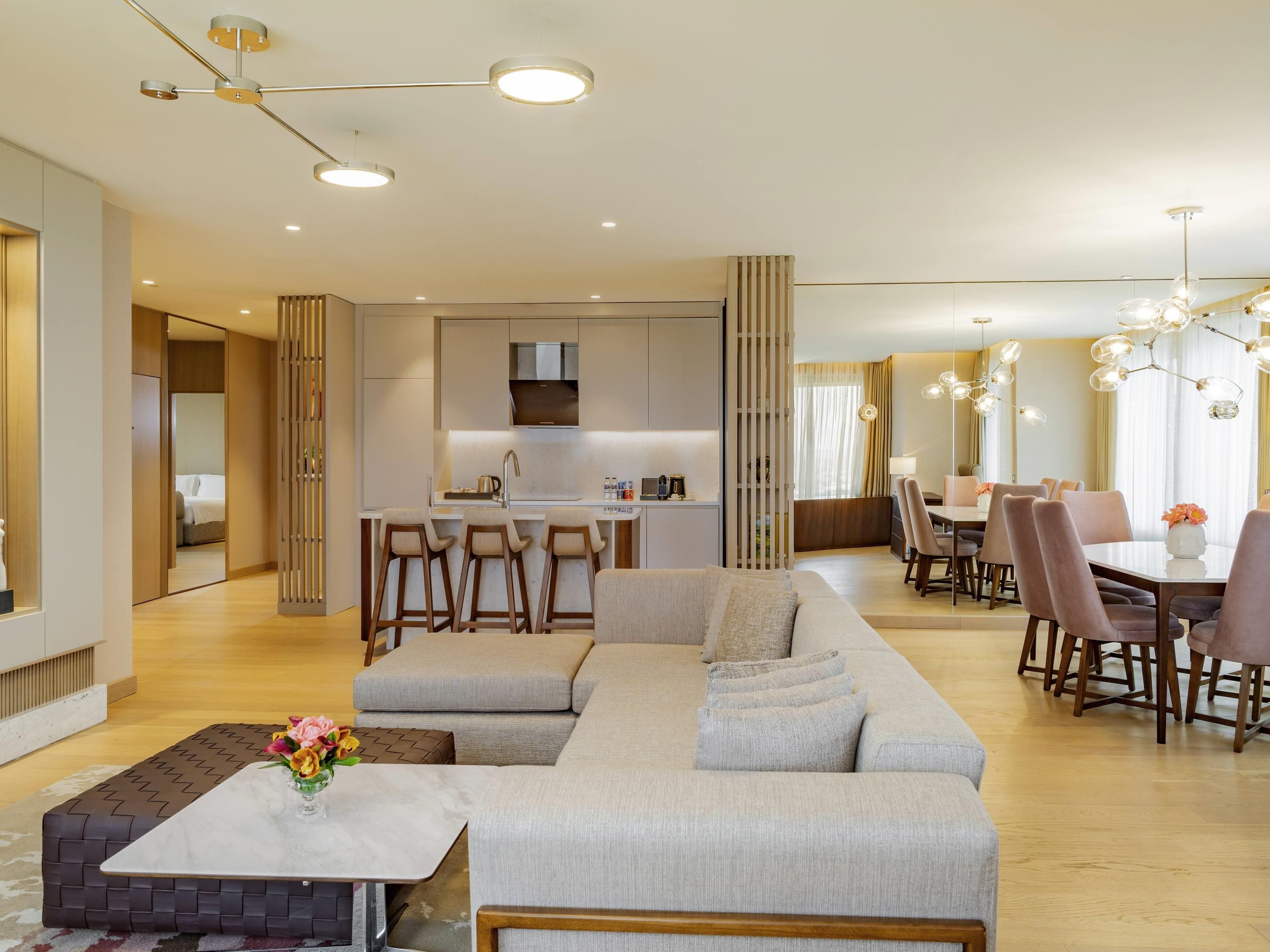 Une chambre d’hôtel moderne dotée d’un espace salon, d’un coin repas et d’une kitchenette.