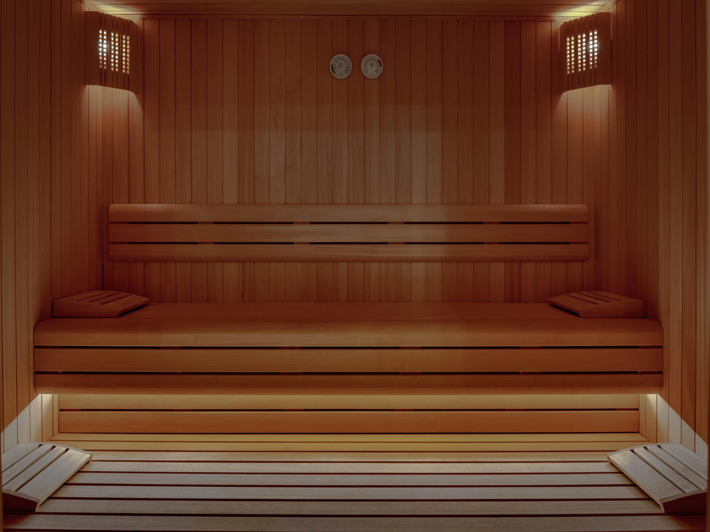 Una sauna de madera con bancos y dos relojes en la pared.