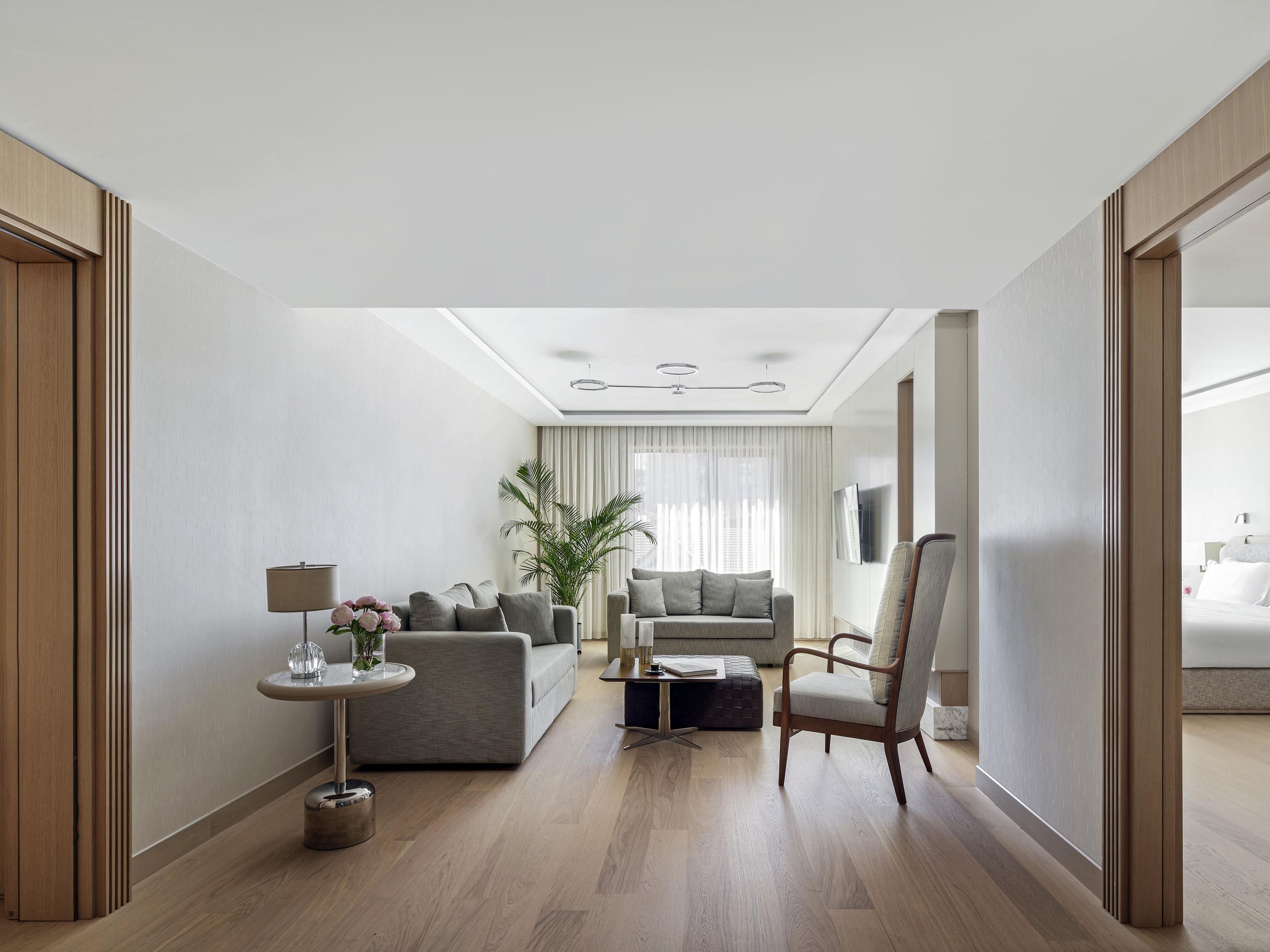 Une chambre d’hôtel moderne, équipée d’un canapé, d’un fauteuil et d’une petite table avec une lampe.