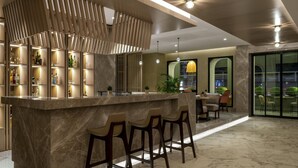 Un área de bar moderna con mostrador de mármol, taburetes y un panel decorativo de madera.