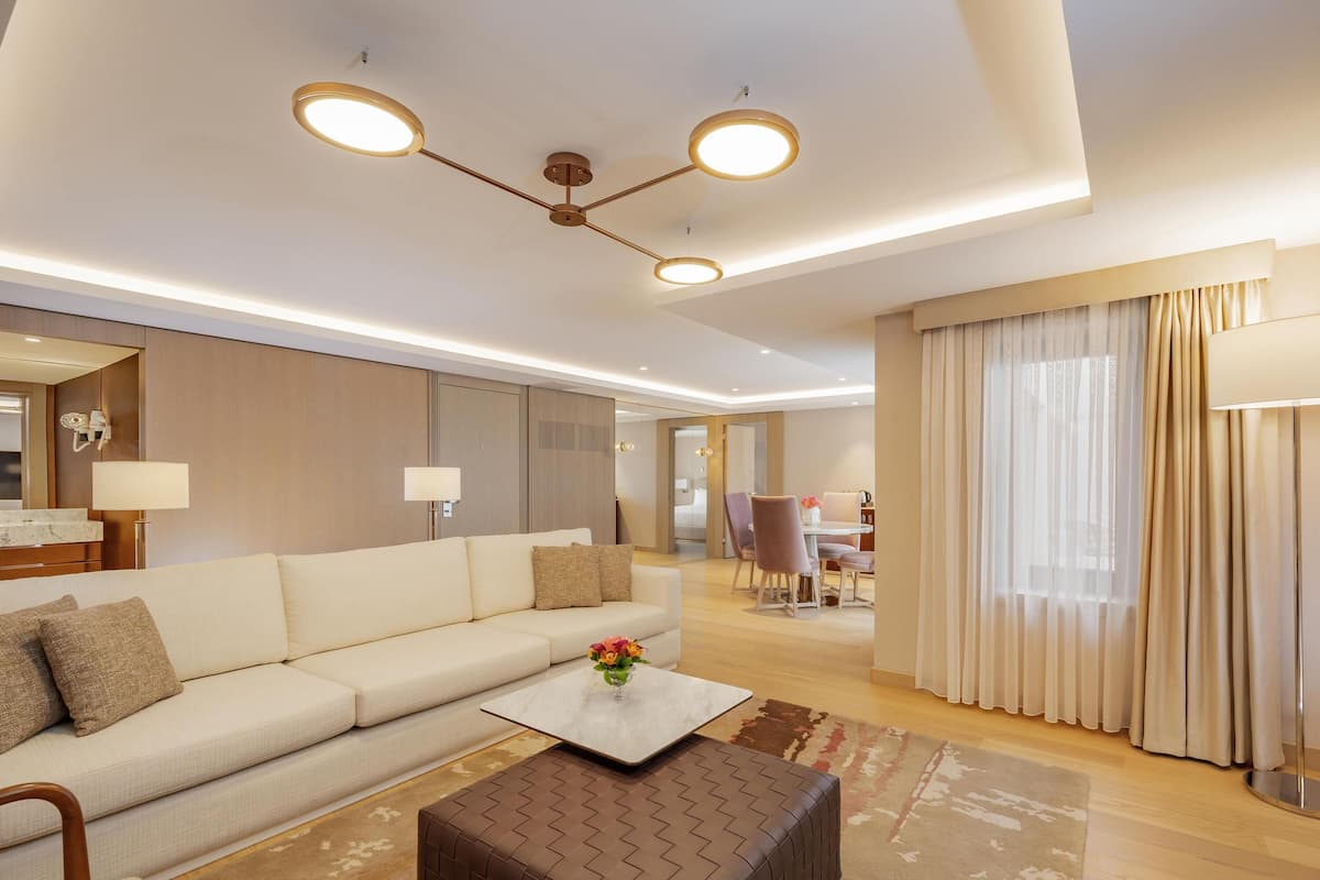 A modern living room with a sofa, ottoman, and a dining area with chairs and a table.