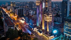 A high-rise hotel with a prominent vertical light display, a visible sign for 'Movenick,' and a view of the surrounding cityscape. - Mövenpick Hotel Istanbul Bosphorus (Istanbul)