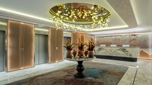 A modern lobby with a marble reception desk, a central decorative table with floral arrangements, and a unique ceiling light fixture. - Mövenpick Hotel Istanbul Bosphorus (Istanbul)