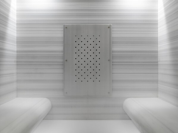 Una habitación con un panel metálico con agujeros, paredes blancas y suelo blanco.