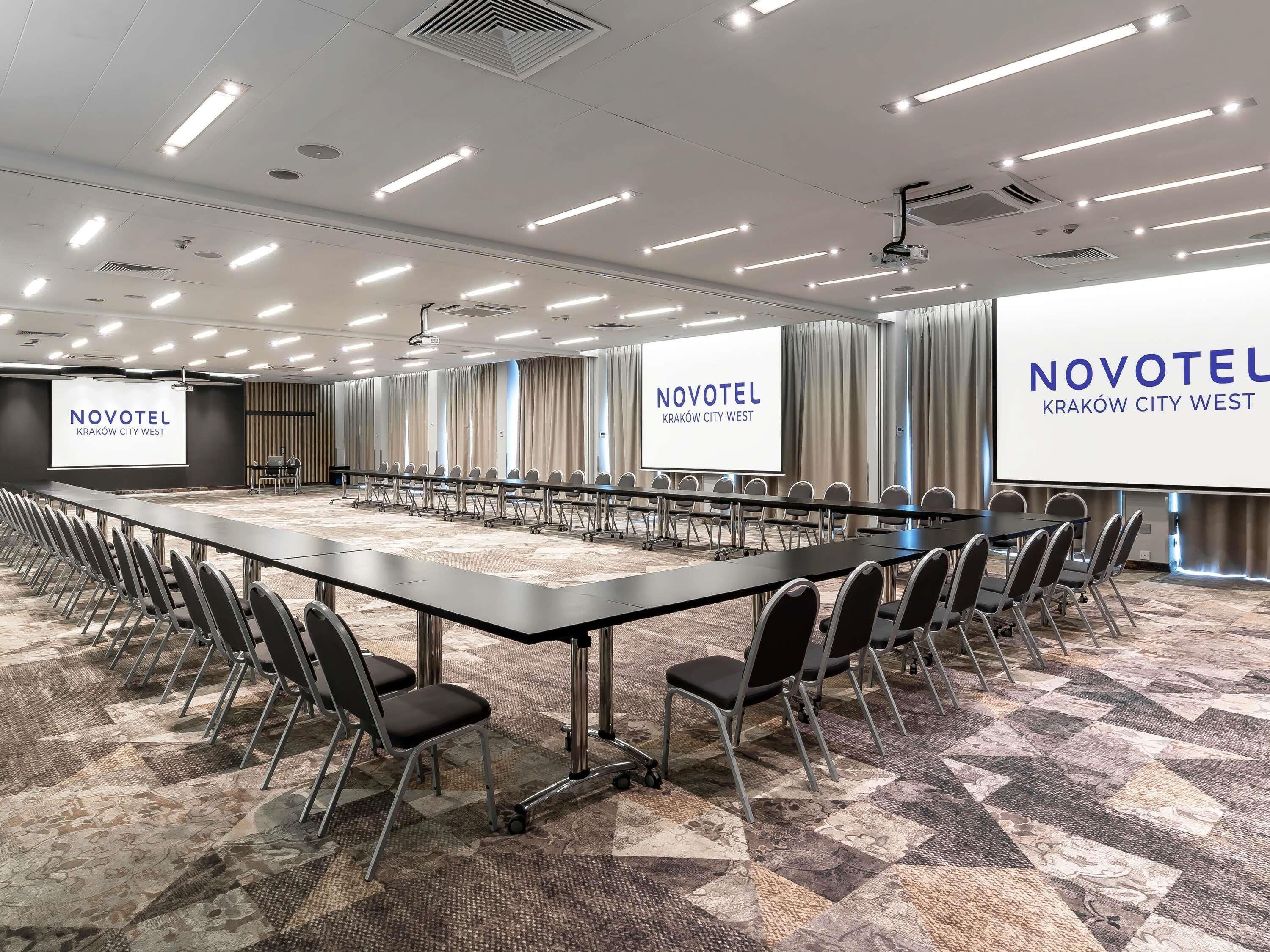Une salle de conférence avec une longue table, des chaises, un écran de projection et un sol recouvert de moquette.