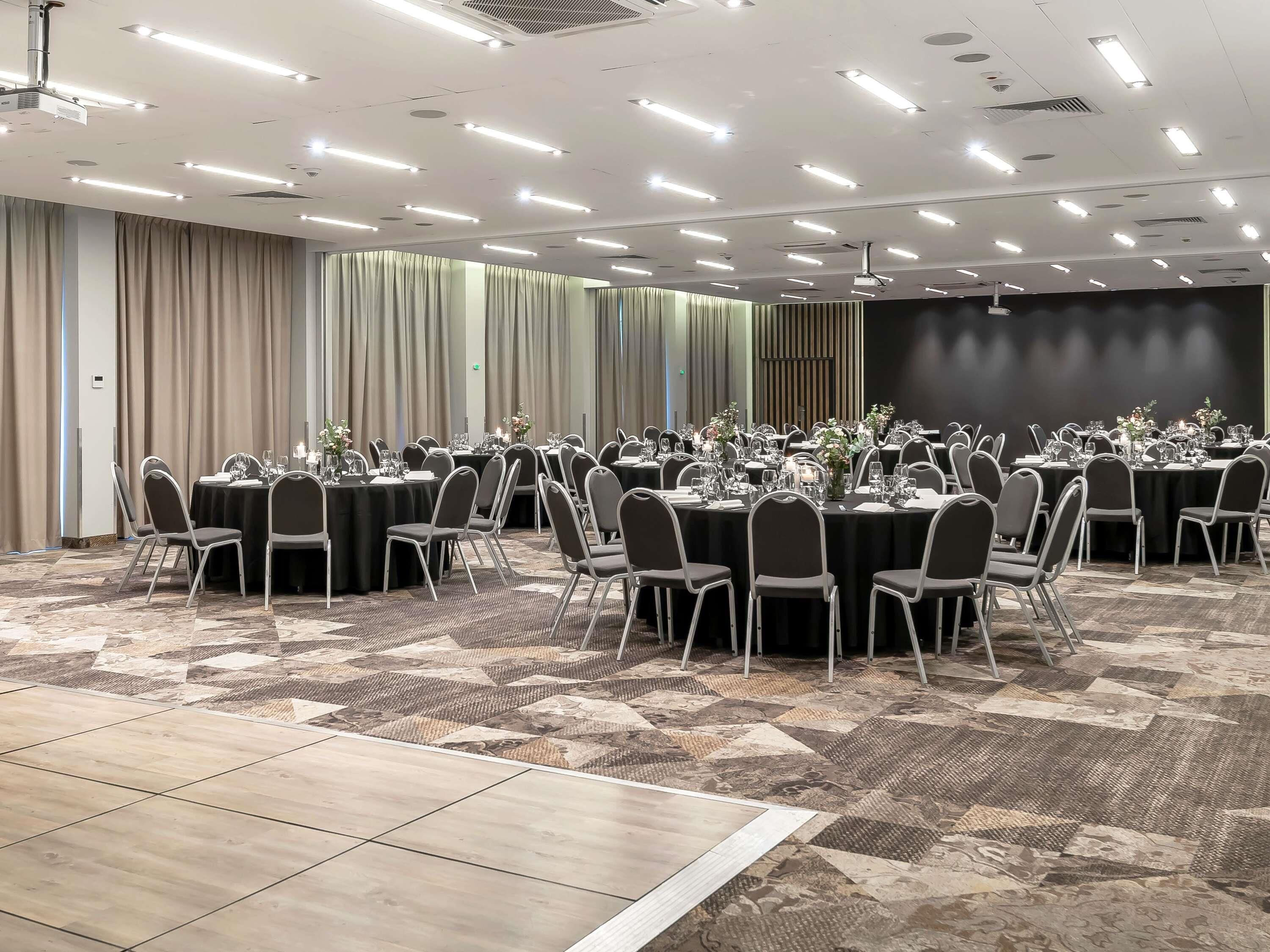 A conference room with multiple tables, chairs, and a projector screen.