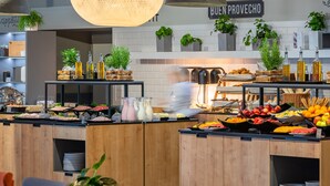 Un espace buffet proposant une variété de plats et de boissons, des meubles en bois et des plantes suspendues.