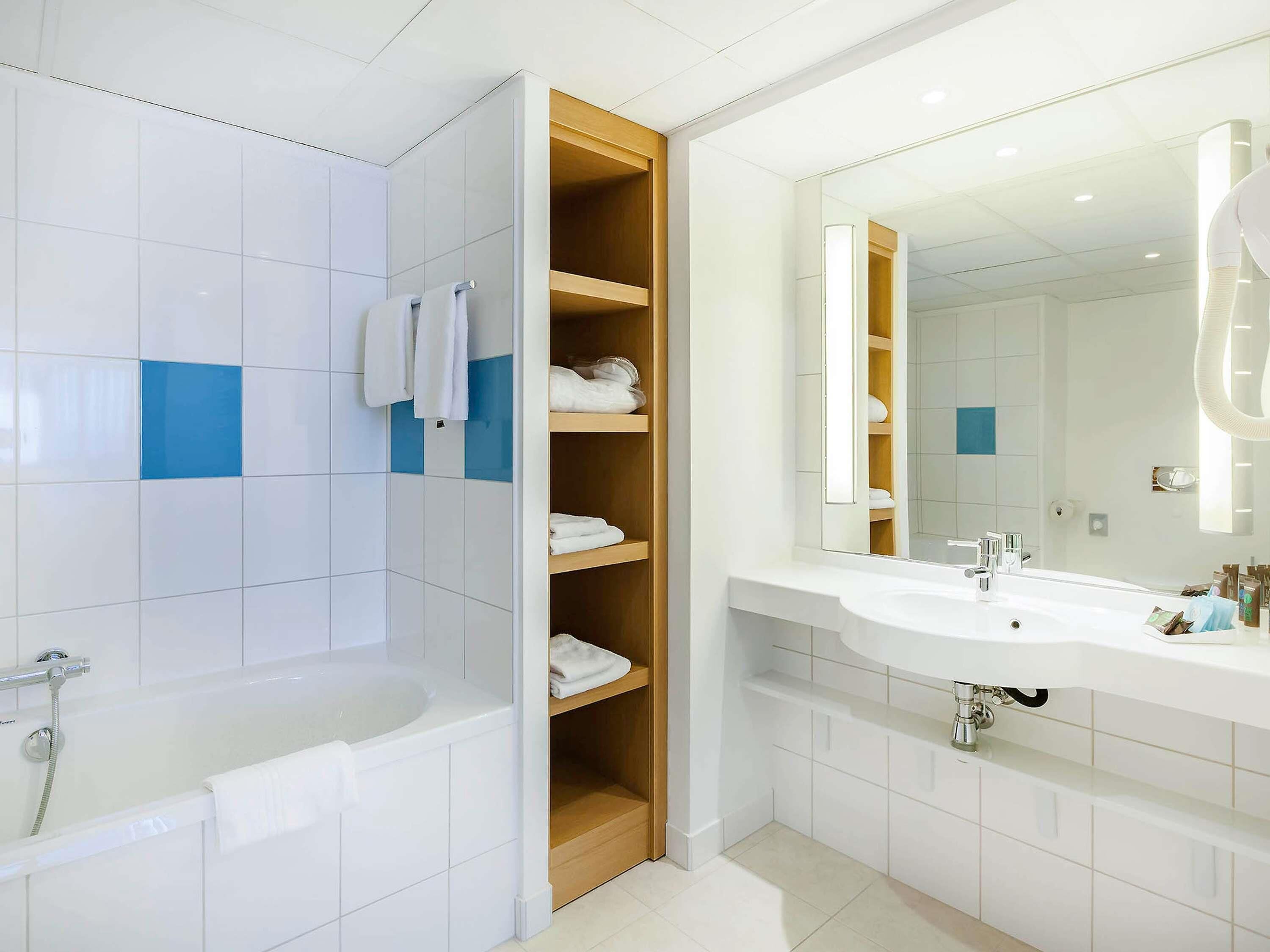 Un bagno moderno con vasca, doccia, lavabo e specchio.