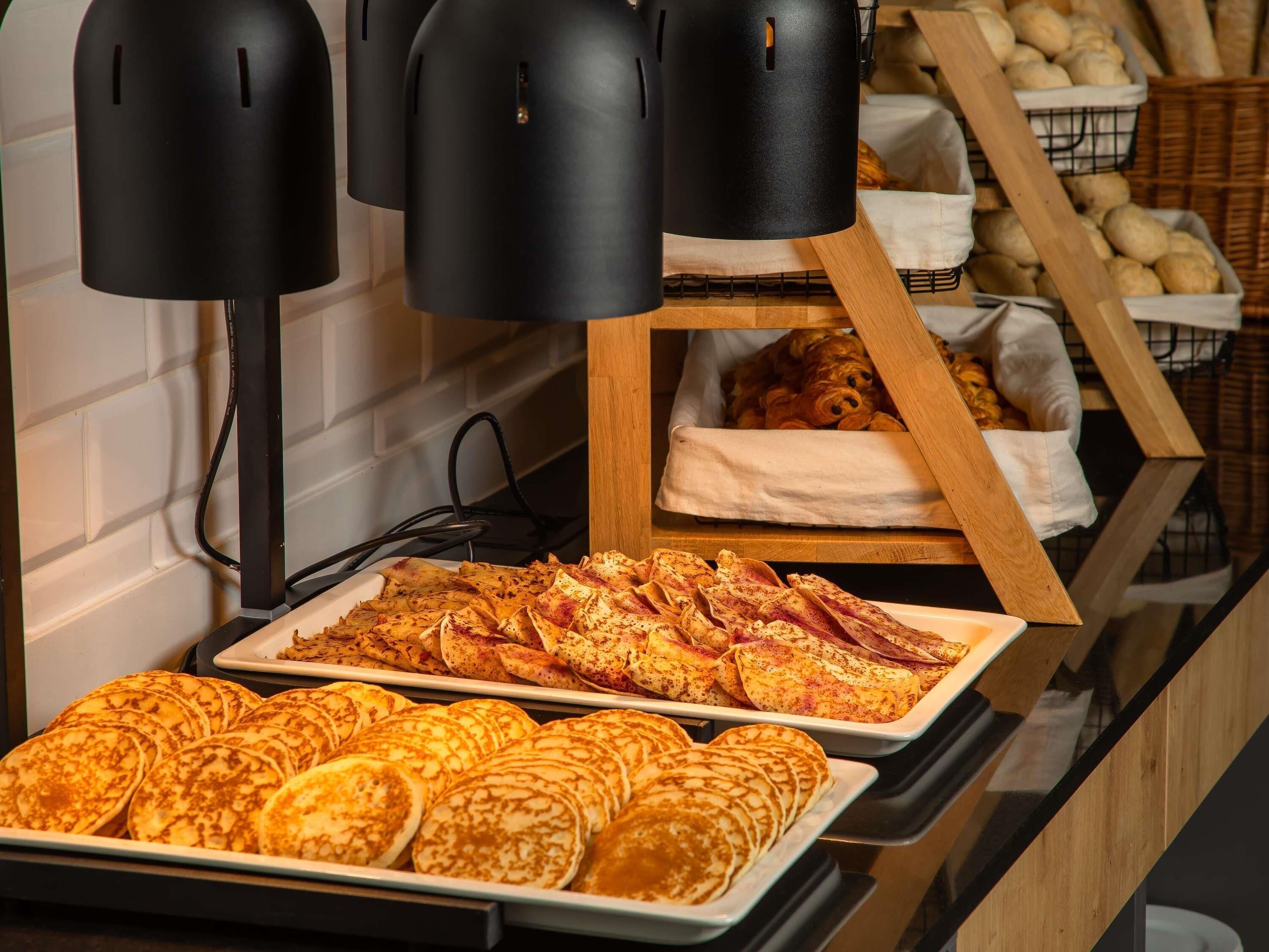 Un buffet proposant une variété de plats, notamment des crêpes et un assortiment de produits de boulangerie.