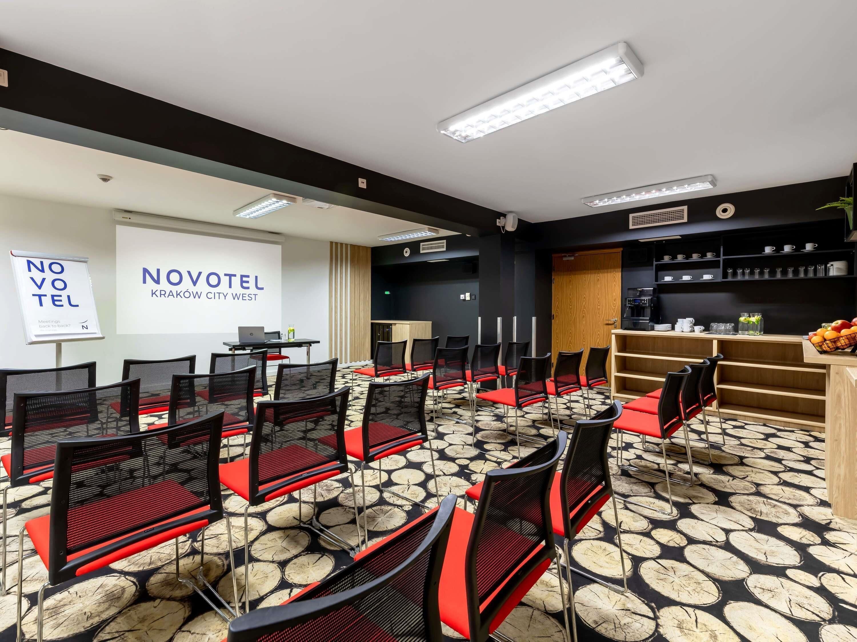 A conference room with rows of chairs, a projector screen, and a coffee station.