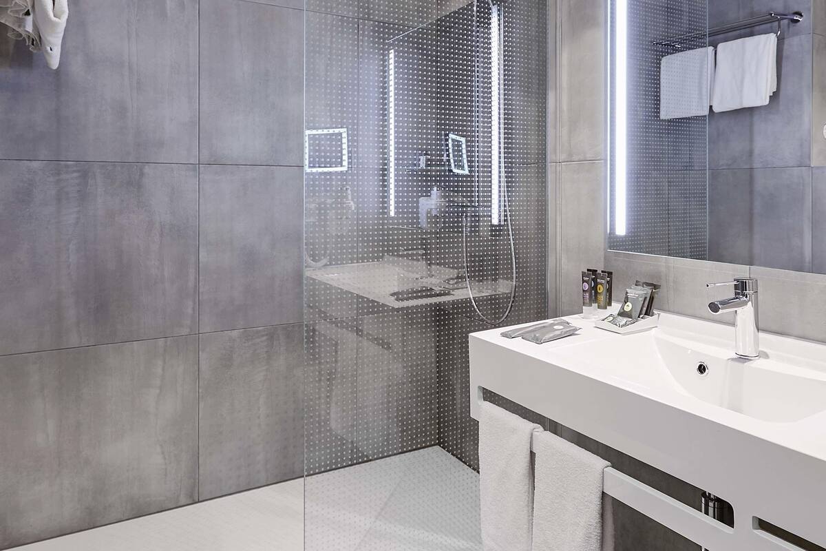 Een moderne badkamer met een grote spiegel, een douchecabine en een wastafelmeubel met een wastafel.