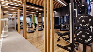 Une salle de sport moderne équipée de tapis de course, de matériel de musculation et dotée de plafonds en panneaux de bois.