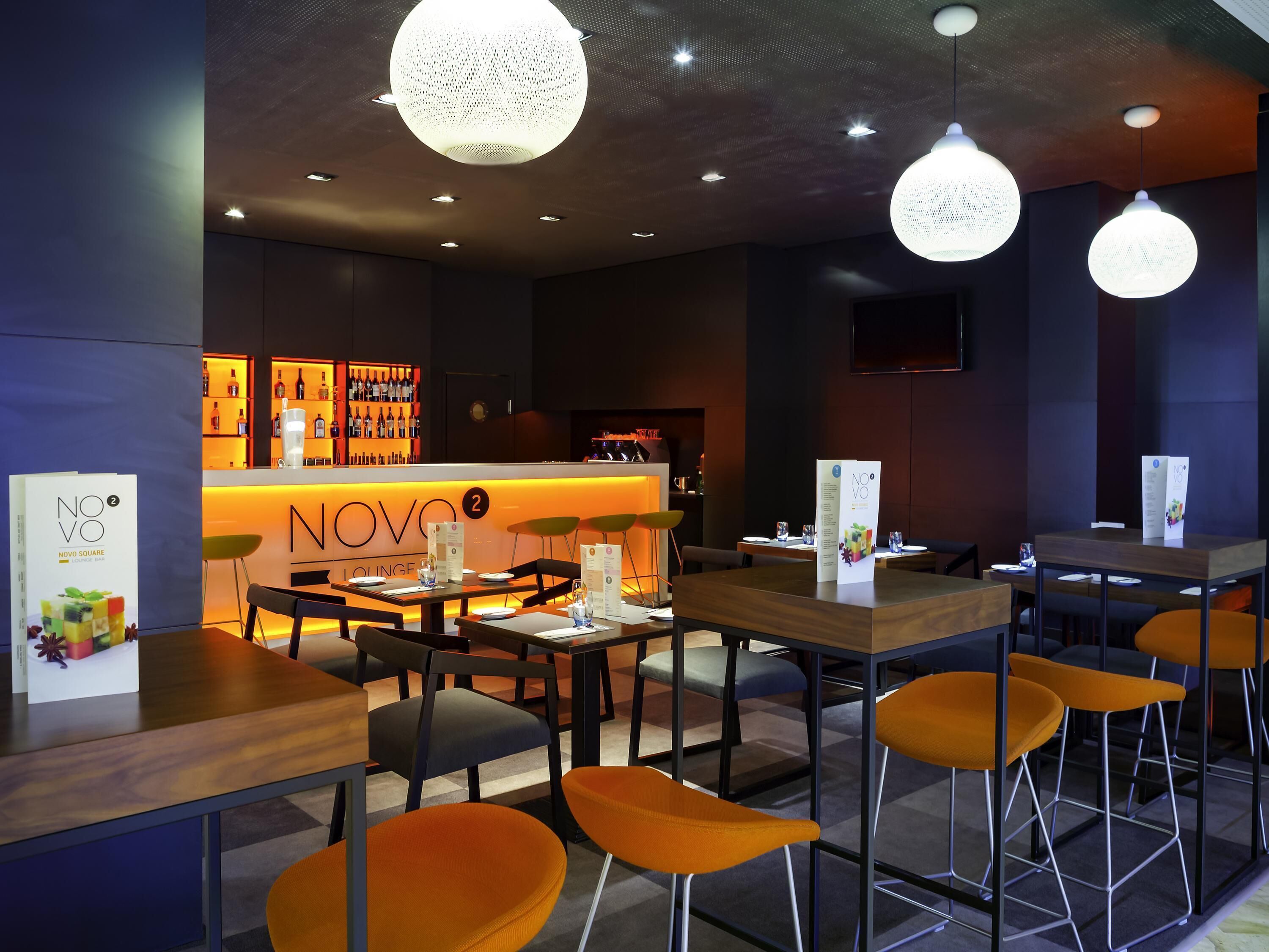 A modern lounge area with tables, chairs, and a bar.