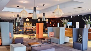 Un hall d’entrée moderne avec des espaces de détente, un comptoir d’accueil et un bar.