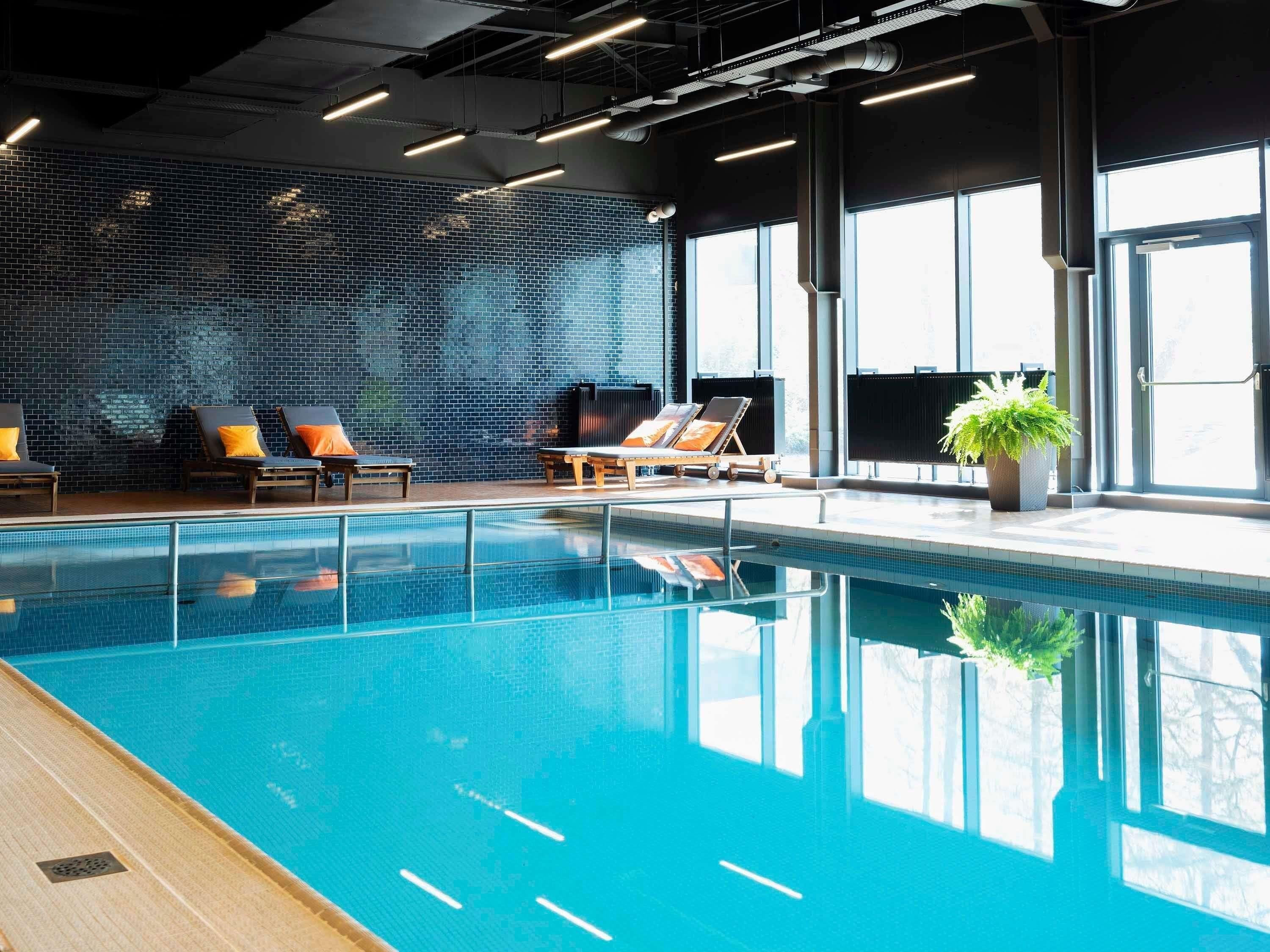 Una piscina interior con sillones de descanso y un ventanal grande.