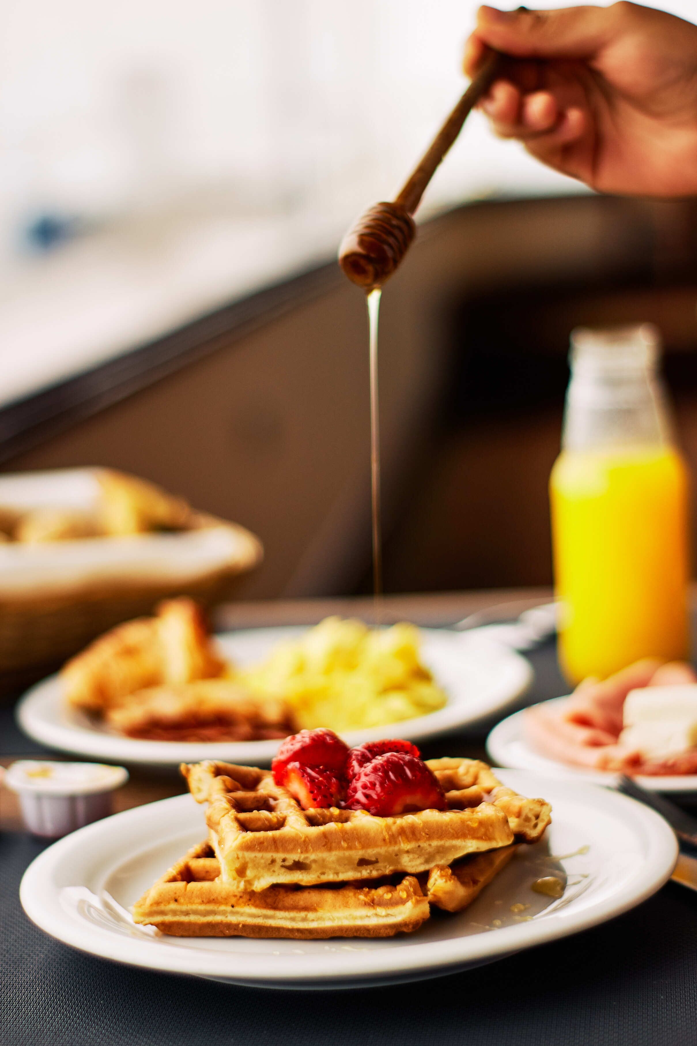 Une table dressée pour le petit-déjeuner avec des gaufres, des fraises et du sirop.