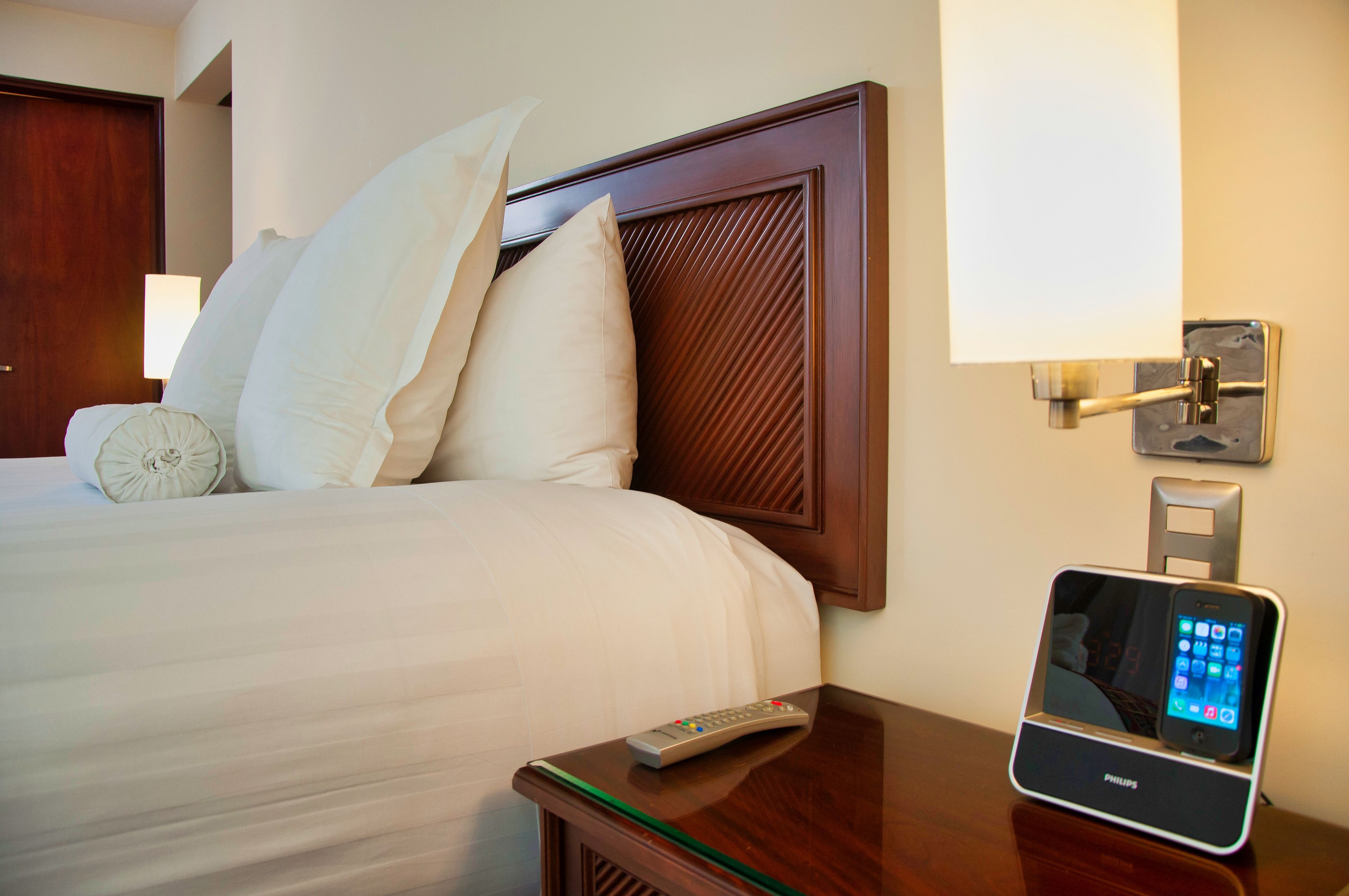 Une chambre d’hôtel équipée d’un lit, d’oreillers, d’une télécommande et d’une station de recharge pour smartphone.