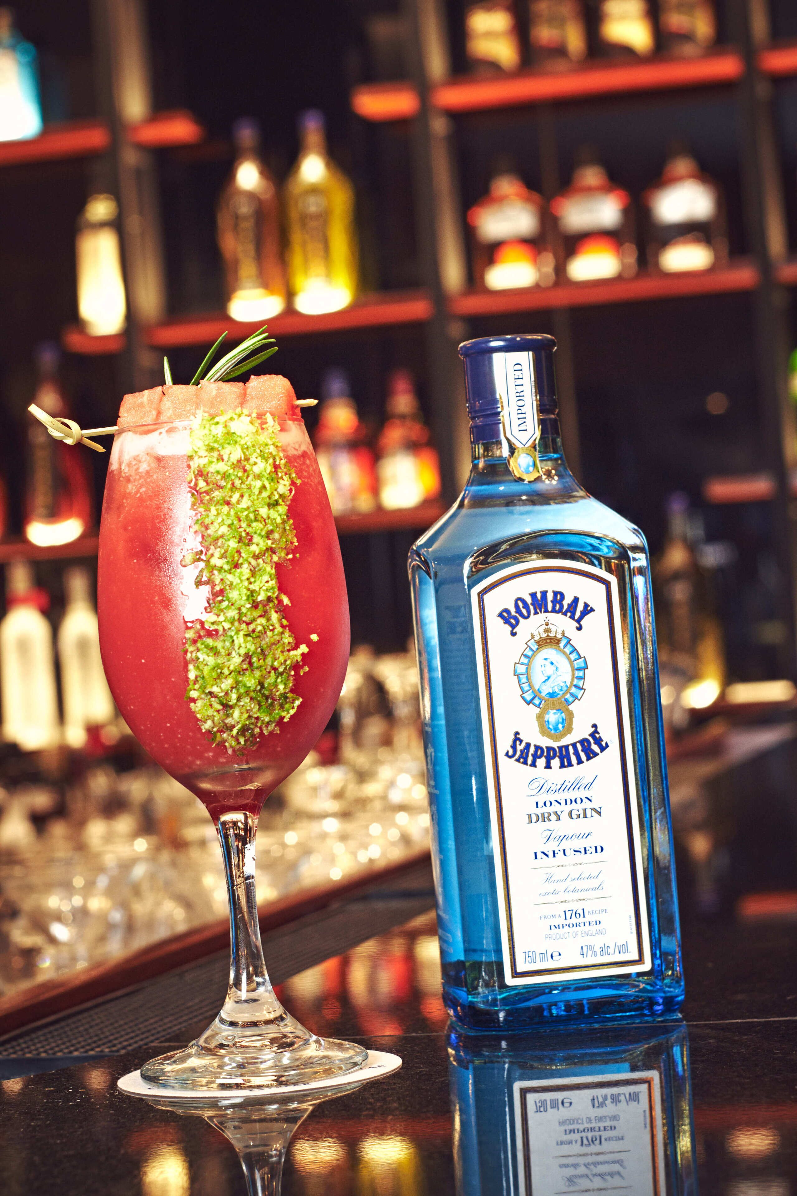 A bottle of Bombay Sapphire gin and a cocktail glass with a garnish.