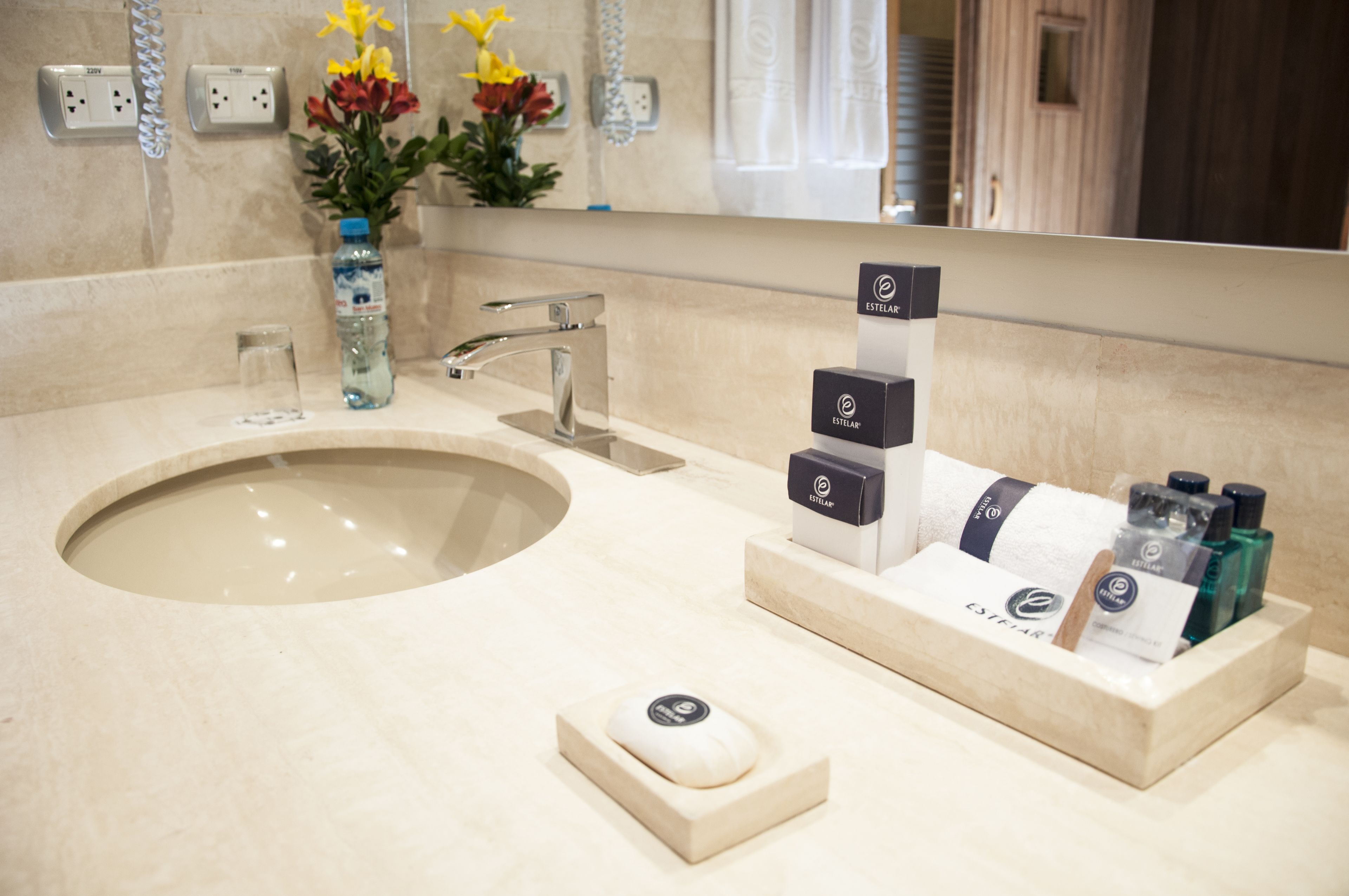 Un baño con un lavabo grande, un espejo y artículos de aseo en la encimera.