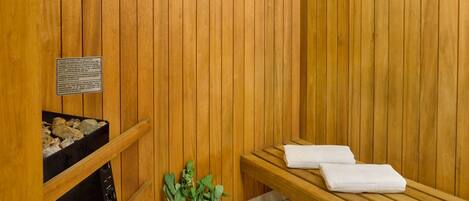 A wooden sauna with a bench, a potted plant, and a sign with safety instructions.