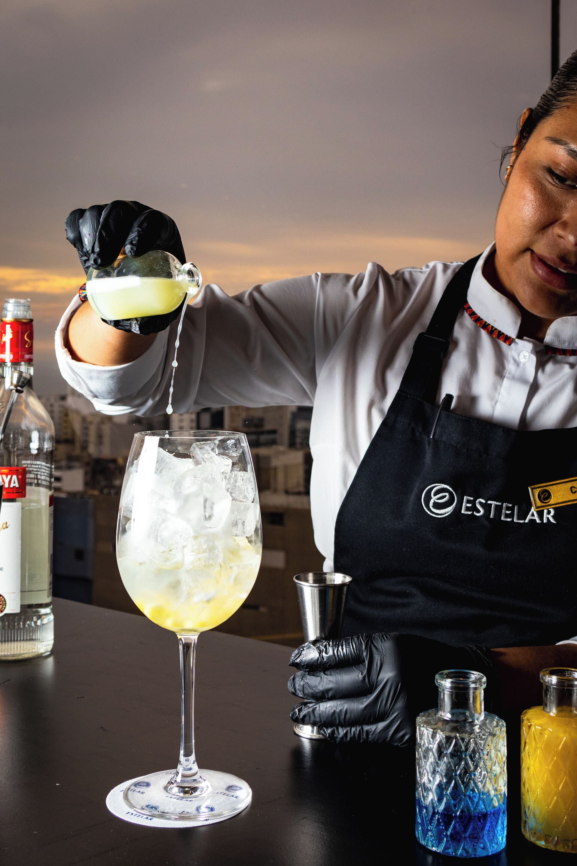 A bartender pouring a drink into a glass with ice.