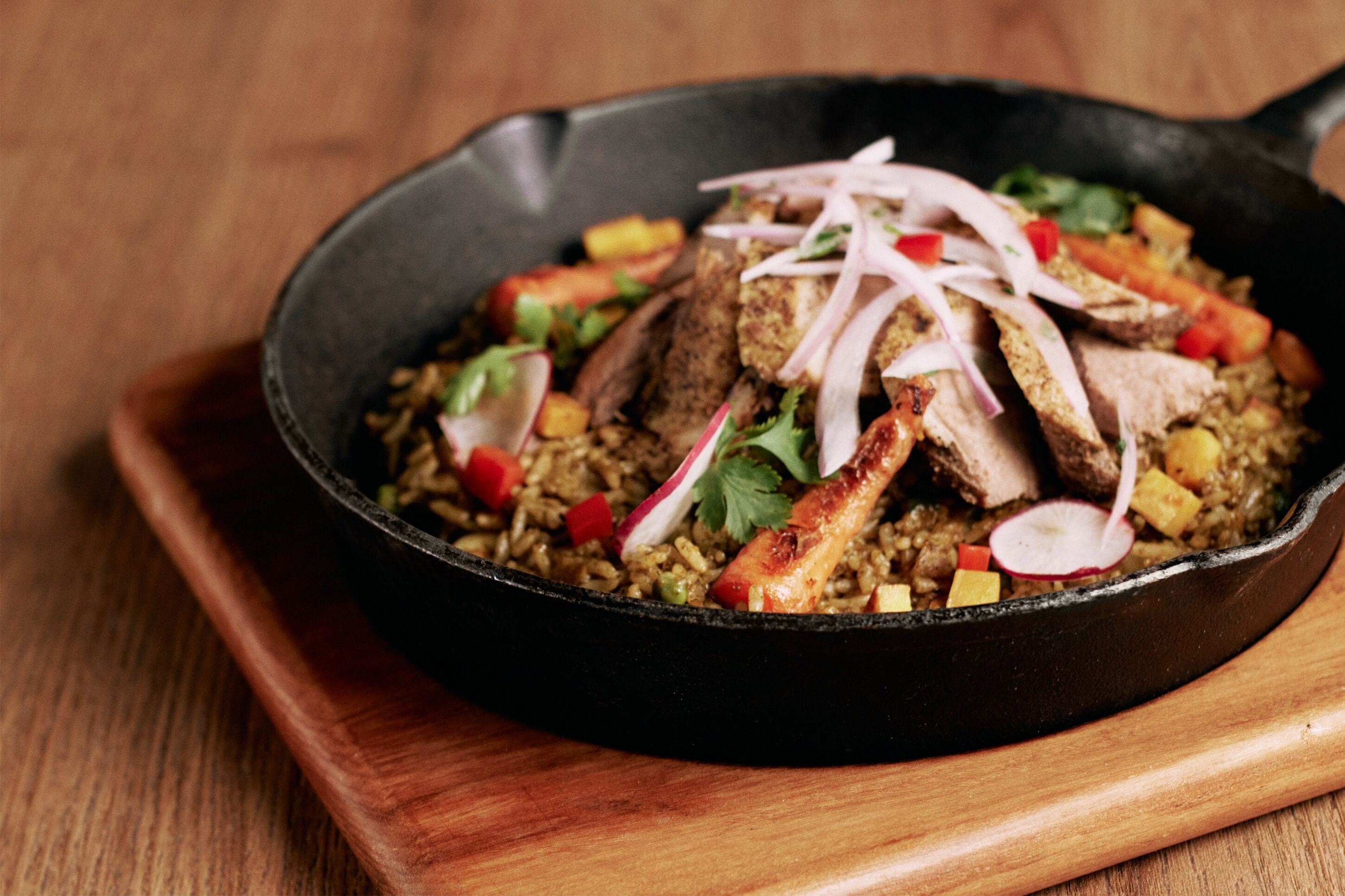 Una sartén con arroz, carne y verduras.