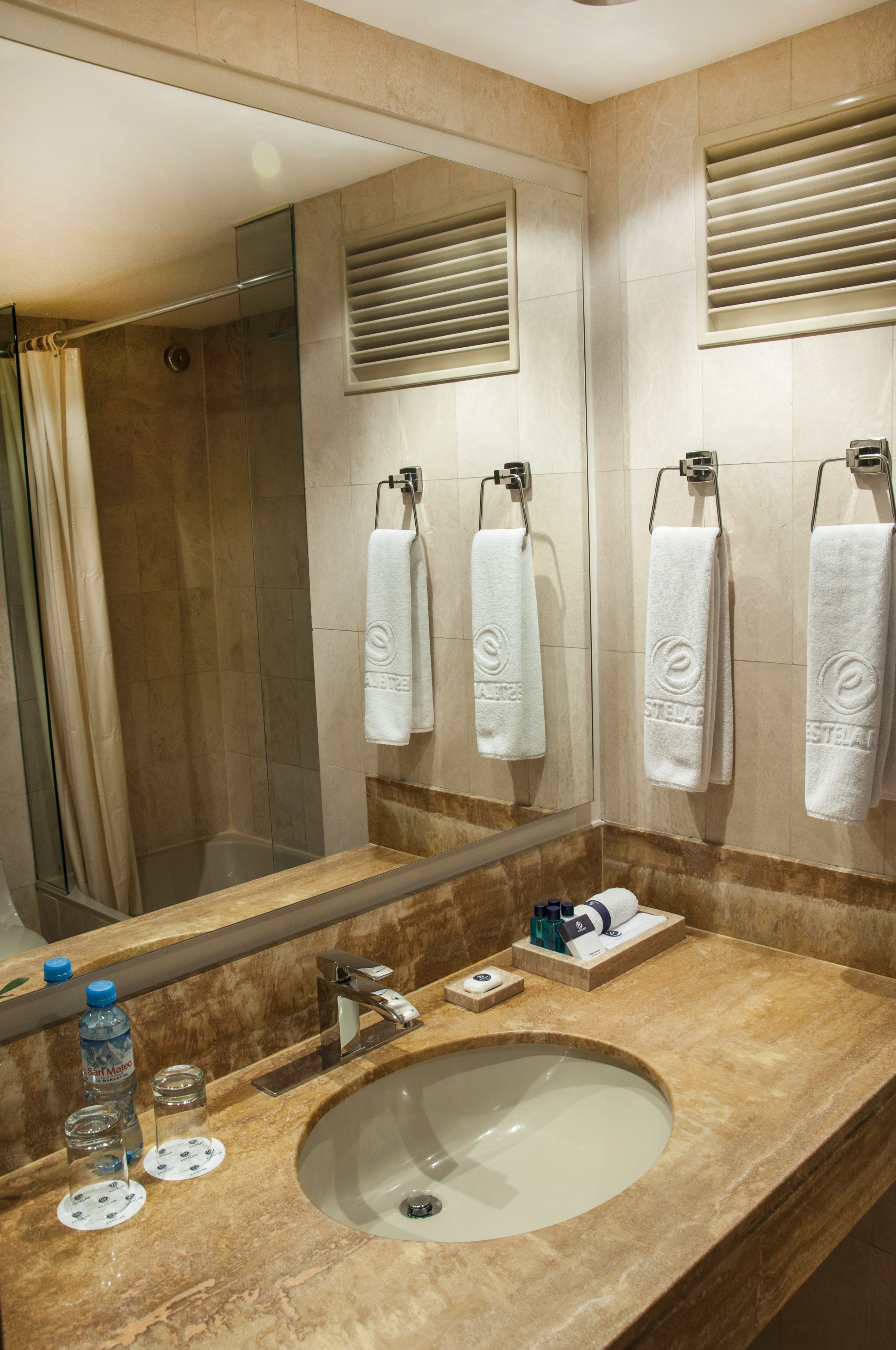 Ein Badezimmer mit einem großen Spiegel, einem Waschbecken und zwei Handtuchhaltern mit weißen Handtüchern.